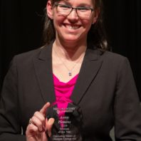 A middle age woman with glasses hold a glass award