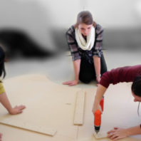 Photo: Three students work at fabricating early table prototype.
