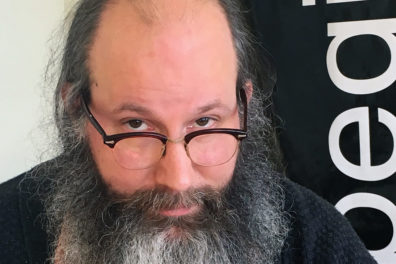 portrait photo of artist looking over his glasses