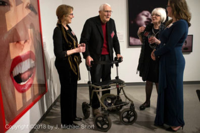 Professor speaks with other guests in front of paintings