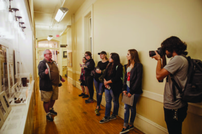 Students in a hallway attending a guided tour by Richard Burrows.
