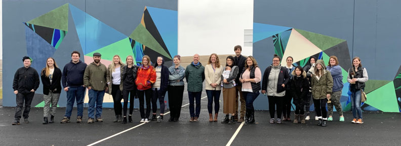 group of people in front of two outdoor murals