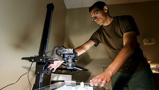 Male student adjusts a camera document scanner.
