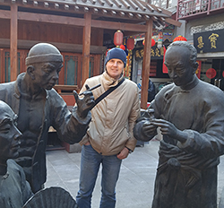 Sergey Lapin stands with life-size statues of 3 men in a market-areapark in Tianjin, China.
