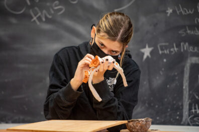 female student working on small clay sculpture.
