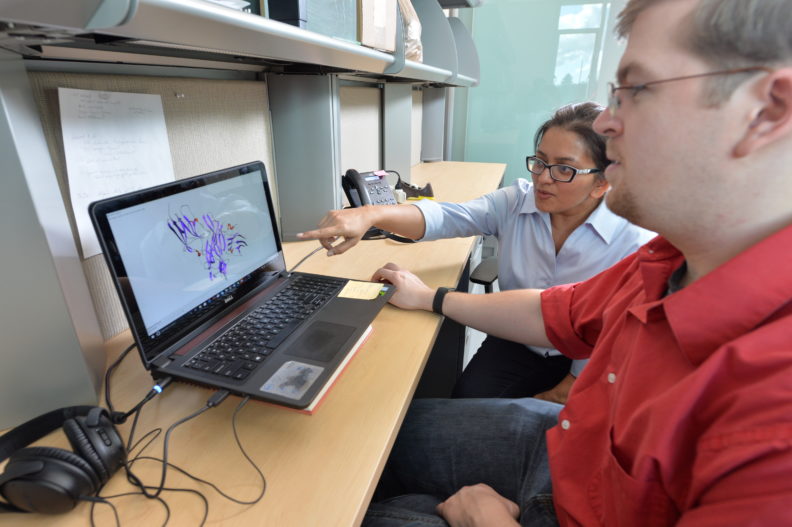 Two graduate students looking at a computer