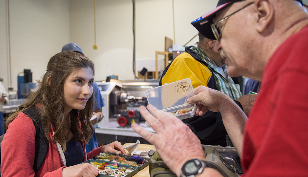 Matese Stevens holds a box of fishing flies and listens to the veteran teaching her.