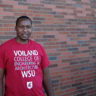 Peter Mugo in front of brick wall