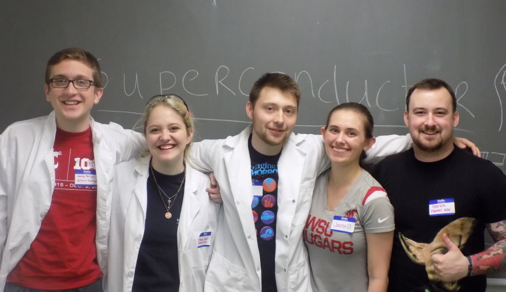 Five students standing in a row with arms around each other's shoulders.