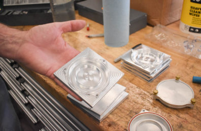 Hand holding up a metal product produced by the WSU shop workers.
