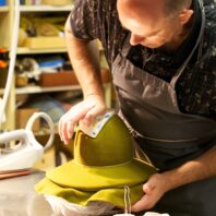 Man shaping a hat to a form.