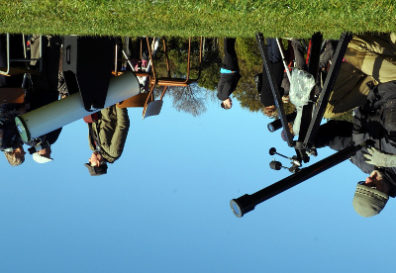 An upside down photo of people looking through telescopes