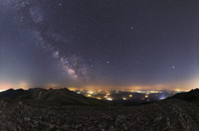 a picture of the night sky from on top of a hill with a city in the background