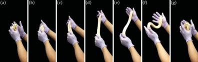 A series of gloved hands stretch white taffy