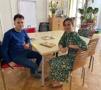young man and woman sitting at a table and looking at the camera
