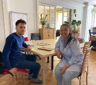young man and a woman sitting at a table, looking at the camera
