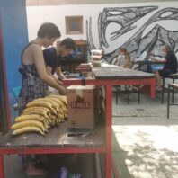 man and woman working at table behind stash of bananas