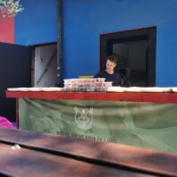 woman working at table with plastic bins of packed lunches