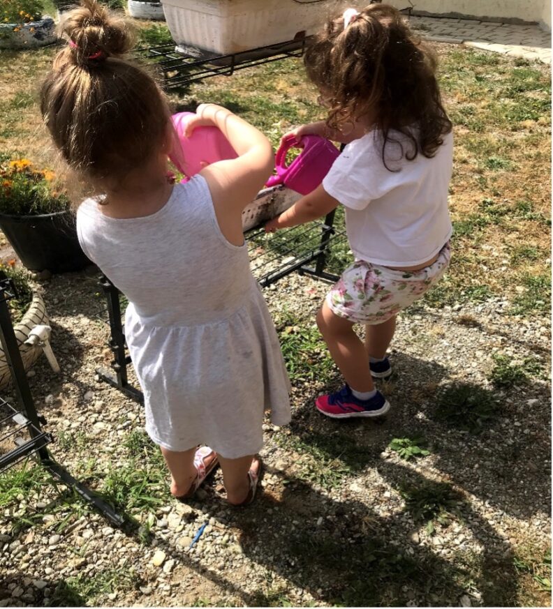 young children watering plants