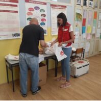 woman volunteer in red vest checking in a client