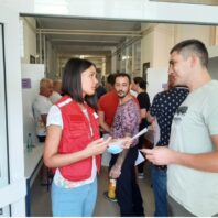 woman in a red vest talking to a younr man