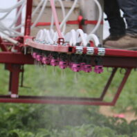 A picture of three rows of spray booms being used in a field.