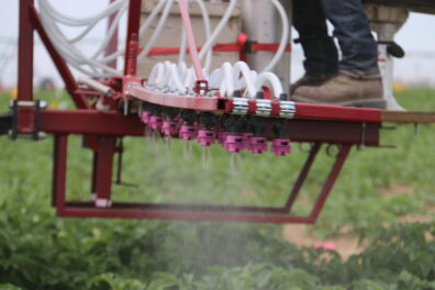 A picture of three rows of spray booms being used in a field.
