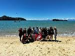 group of students standing on a beach holding a WSU flag