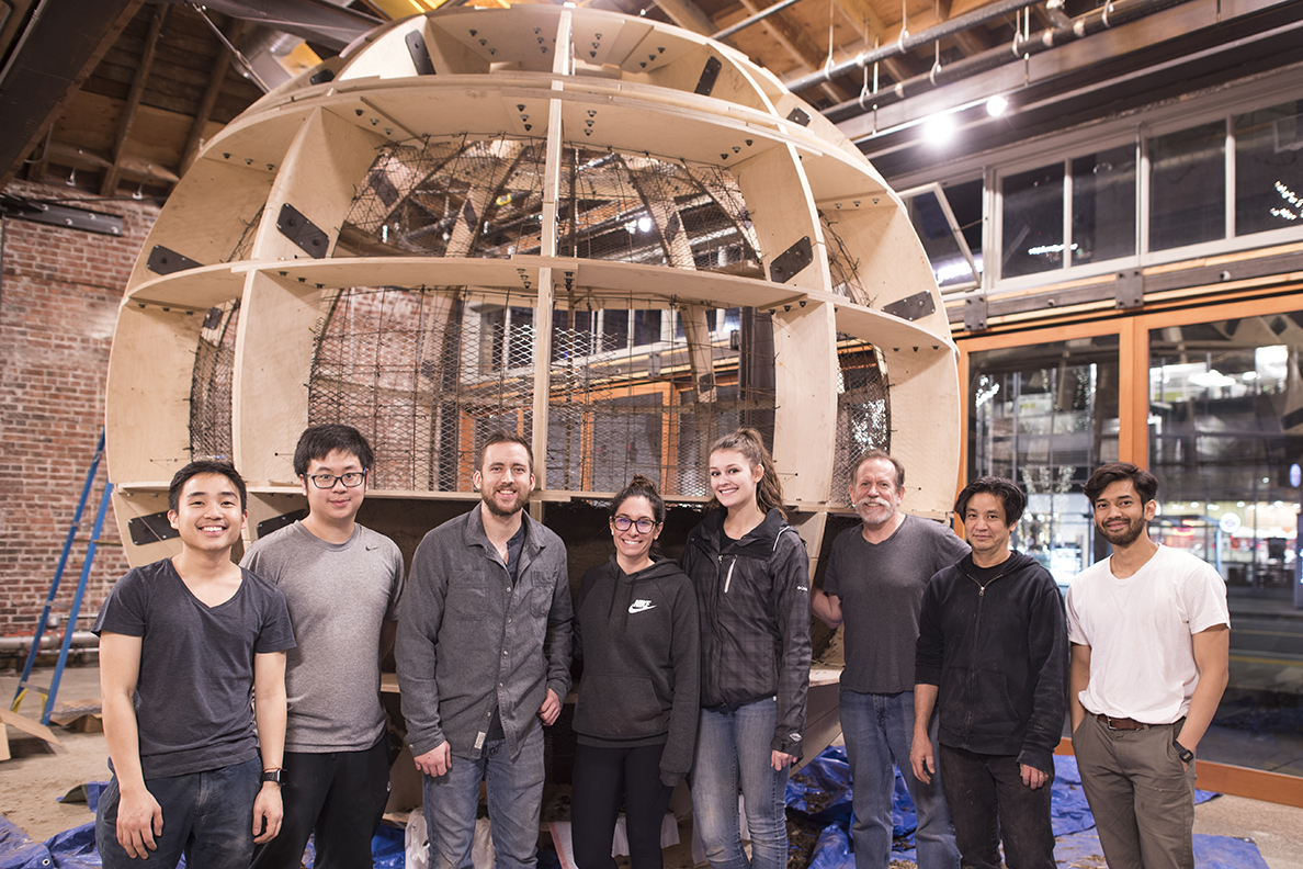 Members of the WSU Circum-ambience project team in front of a globe-shaped, wood-frame structure.