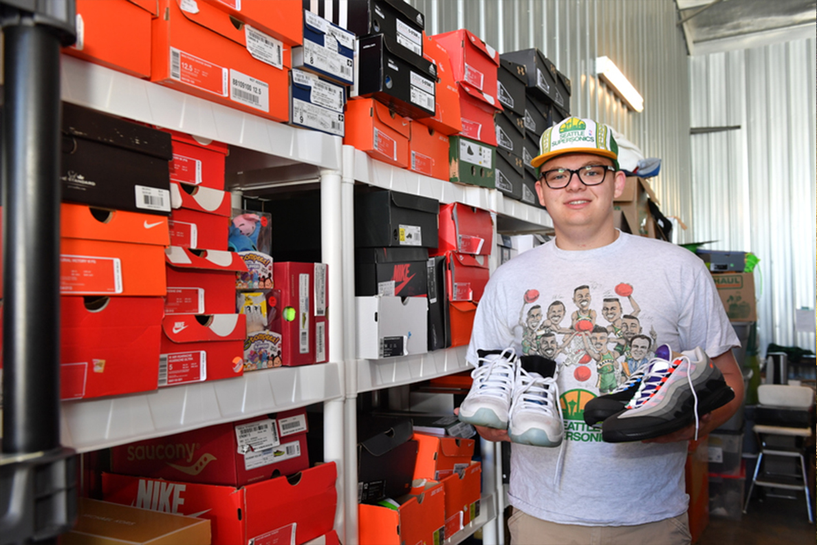 A photograph of Dante Ludlow in a warehouse with an inventory of shoe boxes