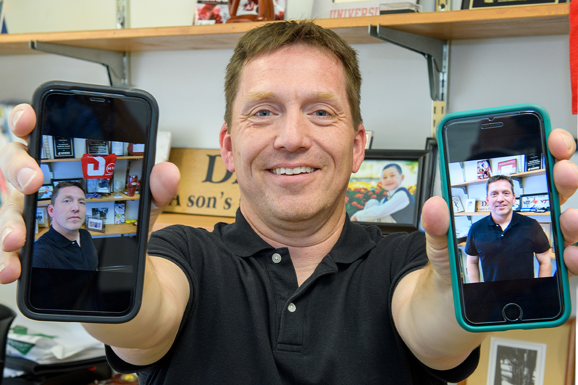 Closeup of Chris Barry holding two phones.