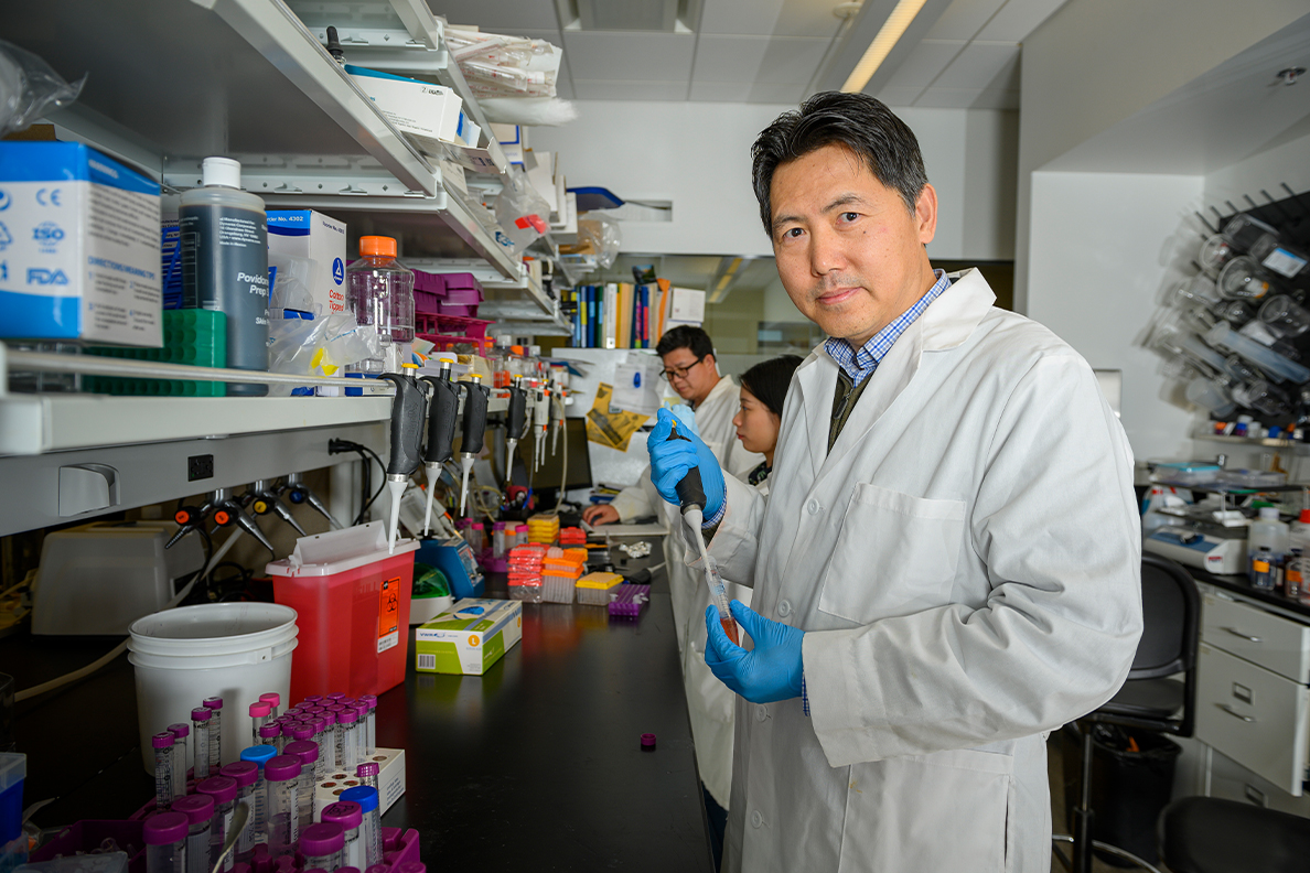 Closeup of Zhenjia Wang with other researchers in the background.