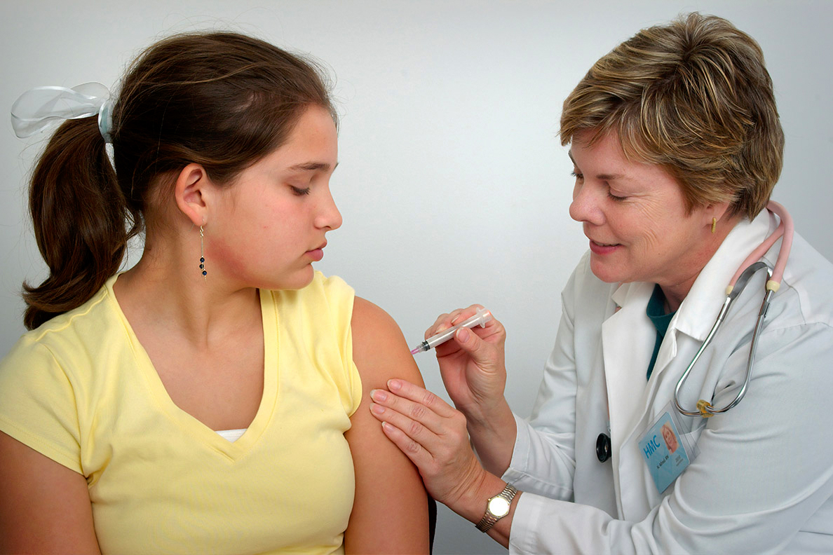 Female doctor giving a shot in the arm of young female patient.