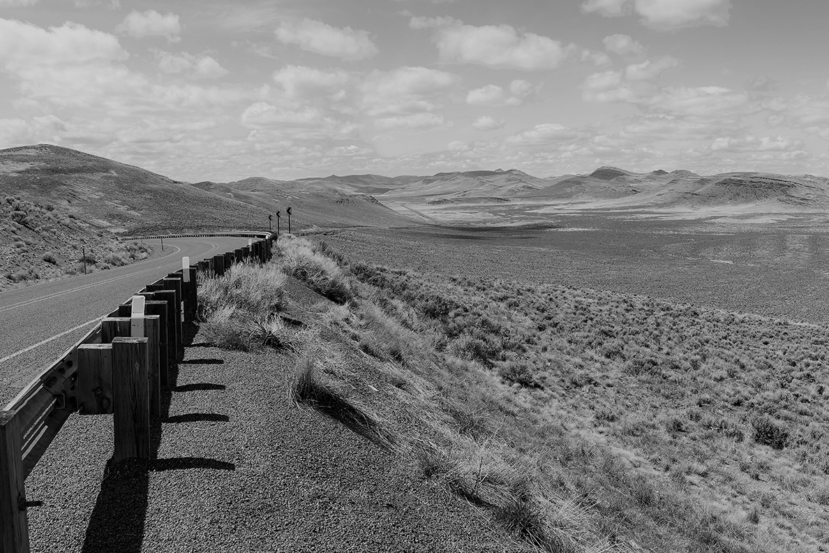 Black and white photo of roadside and rural landscape in Malheur County, Oregon.