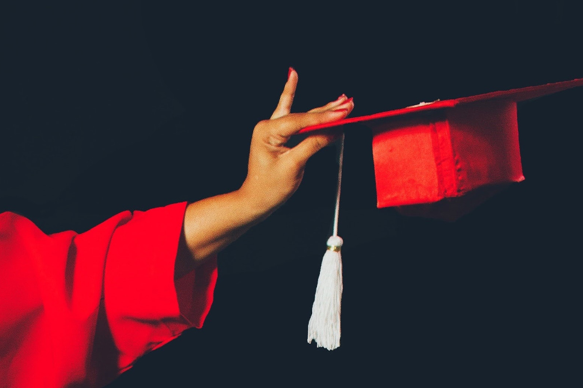 Closeup of a hand holding a graduation cap.