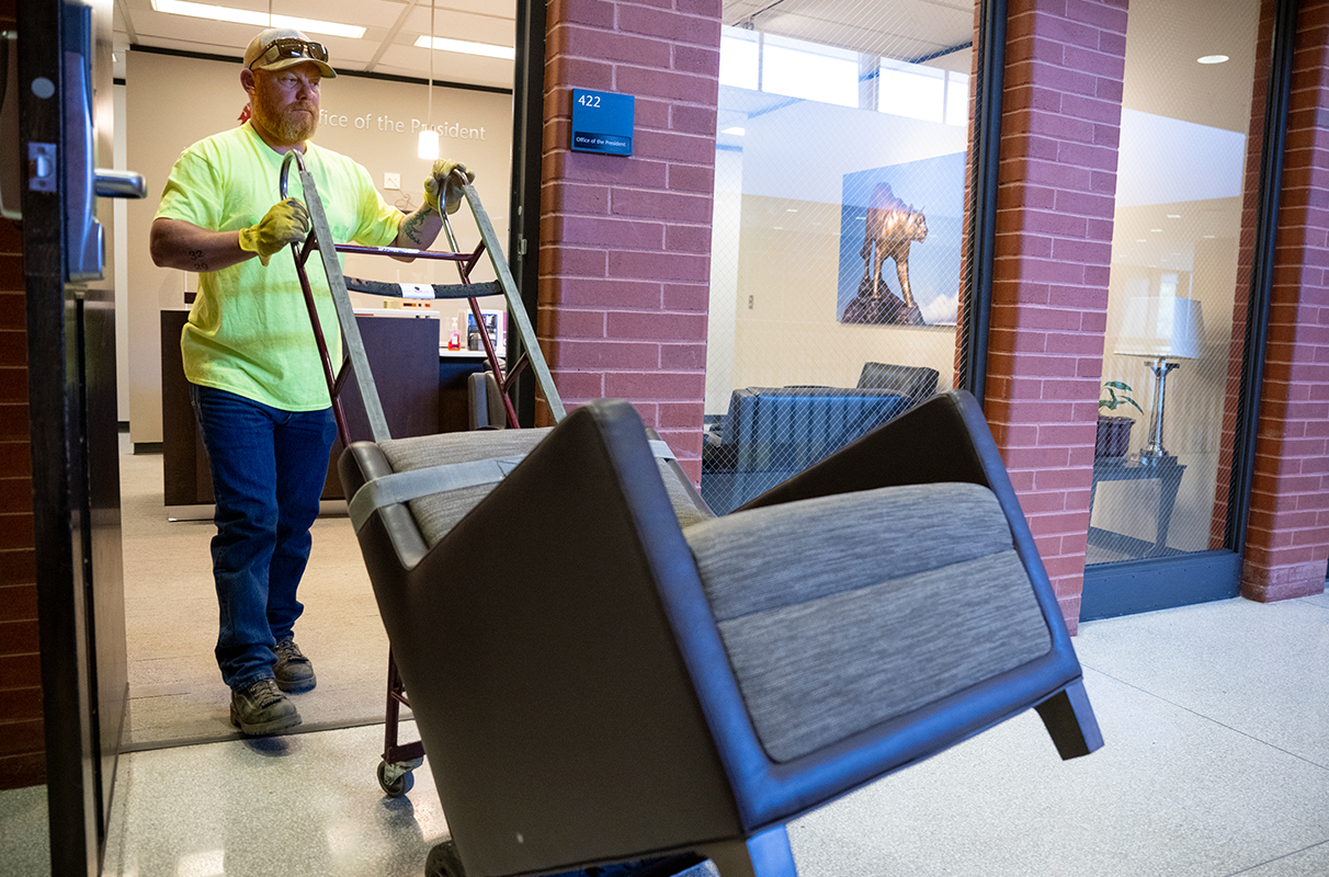 Someone moving a large chair on a dolly through a doorway.