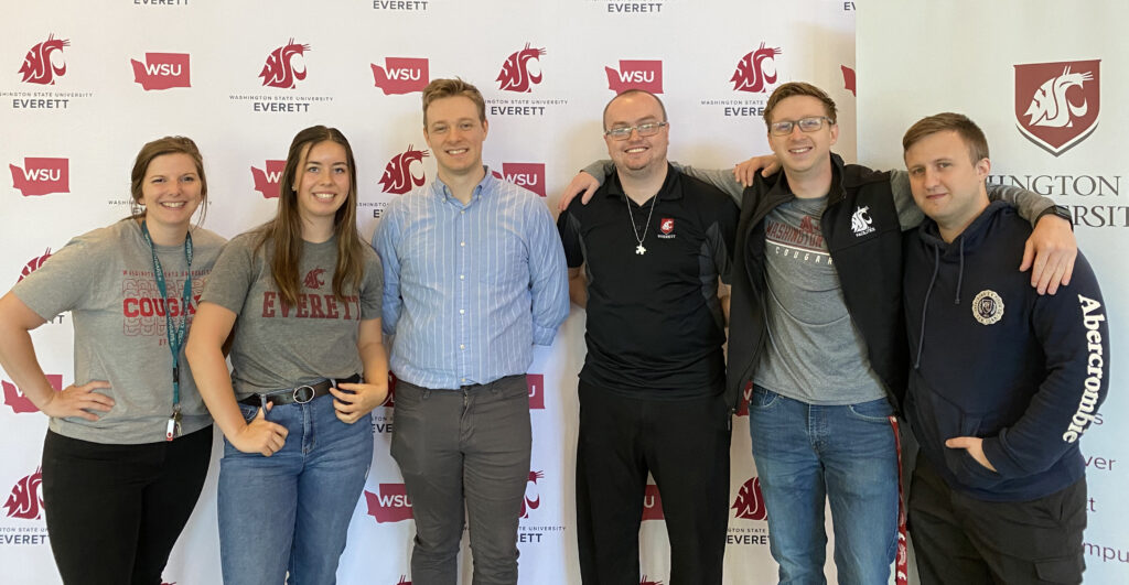 People posing for a group photo in front of a WSU Everett-themed backdrop.