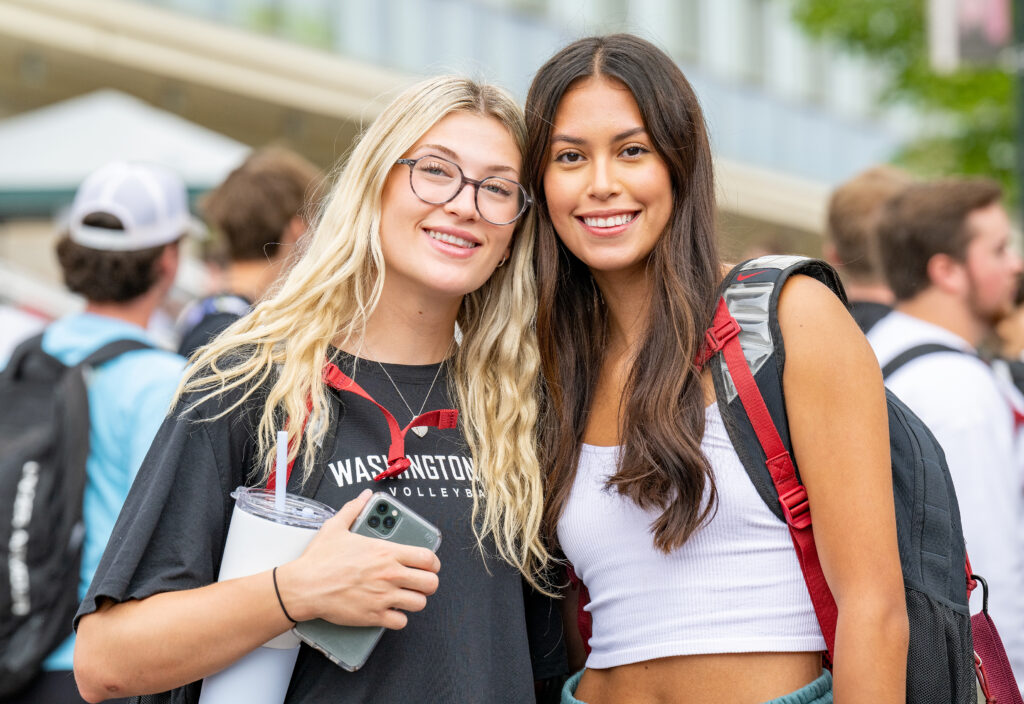Two WSU Pullman students stop outside and pose for the camera.
