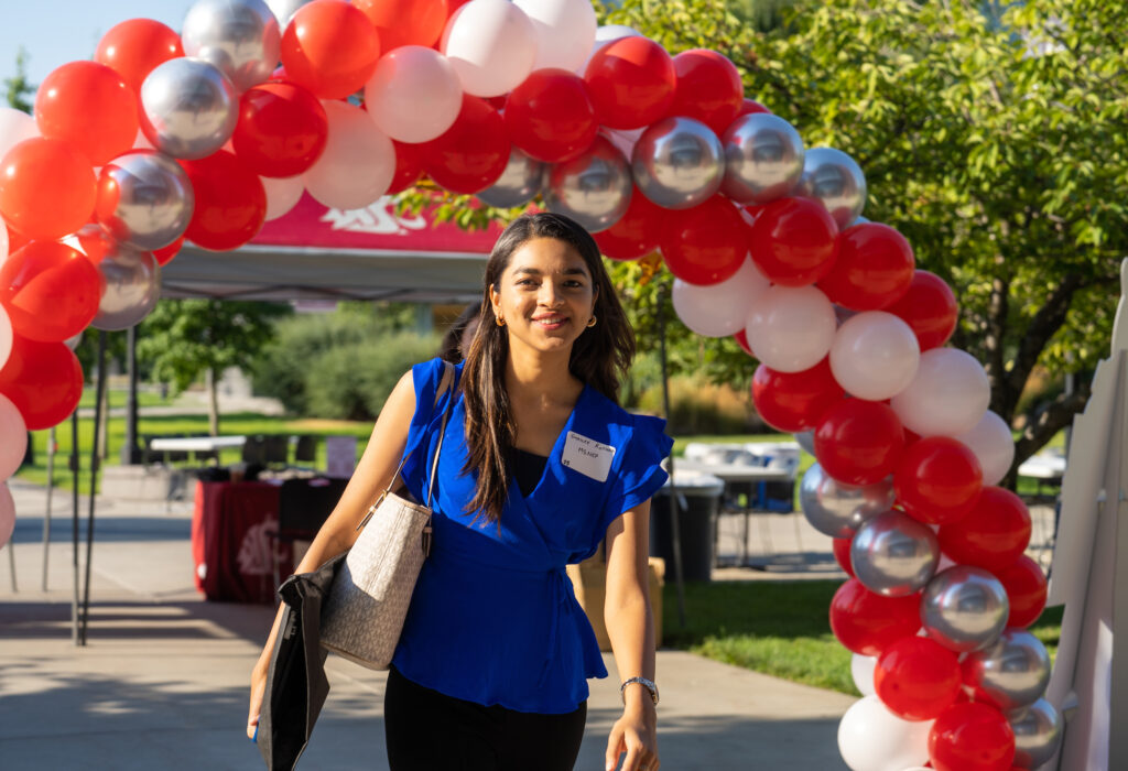 A WSU Spokane student walking under a balloon archway.