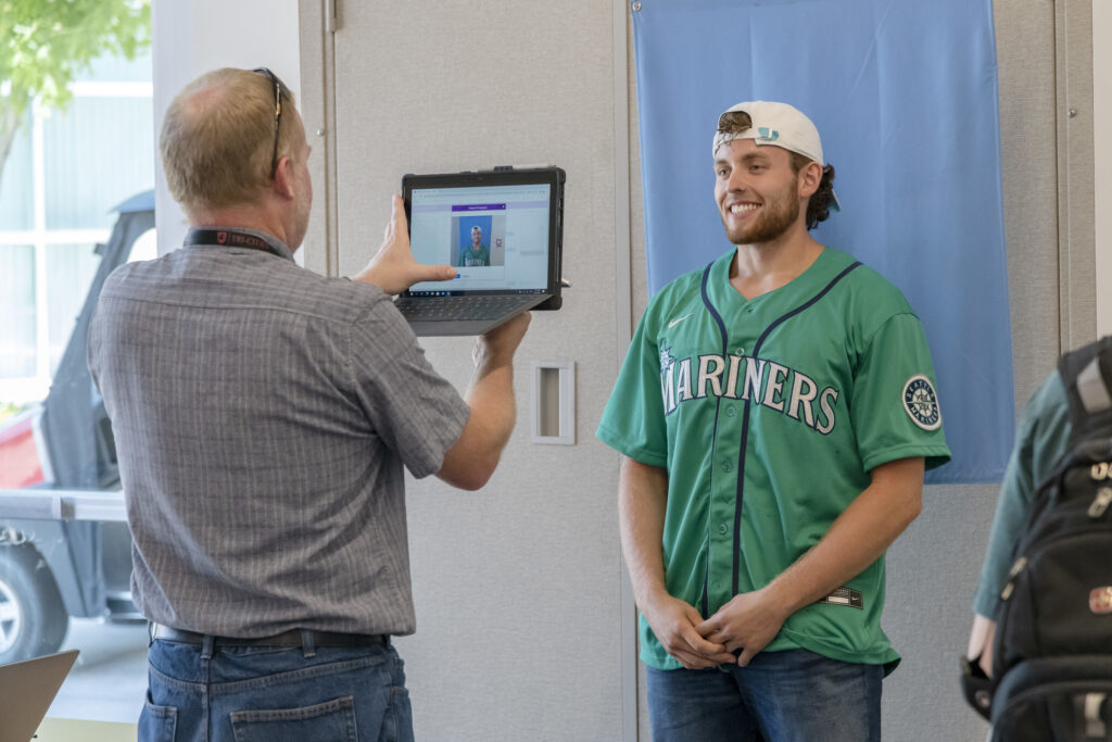 Someone takes a picture of a WSU Tri-Cities student against a blue backdrop.