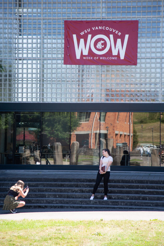 Student posing for a cell phone photo outside a building on the WSU Vancouver campus.