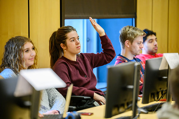 Students in class with one student raising their hand.