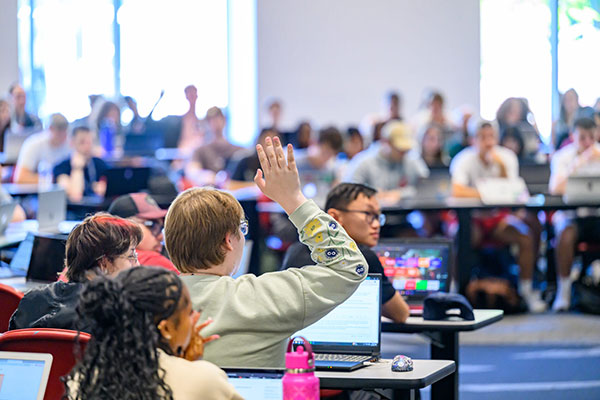 Students in class with one student raising their hand.