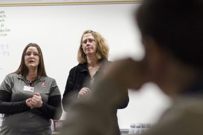 Two nursing students standing in front of a classroom.