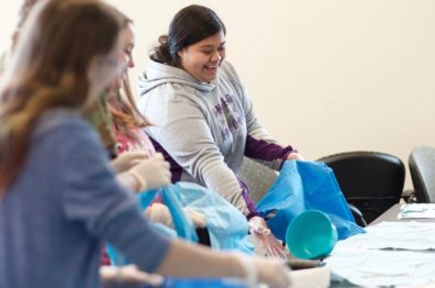 Student laughing while trying to flip an object onto a sterile mat during Upward Bound demonstration.