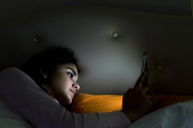teen looking at her phone in bed