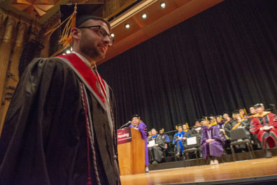 Graduate in cap and gown walking toward the stage