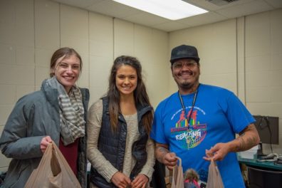 Three people holding bags of donated goods