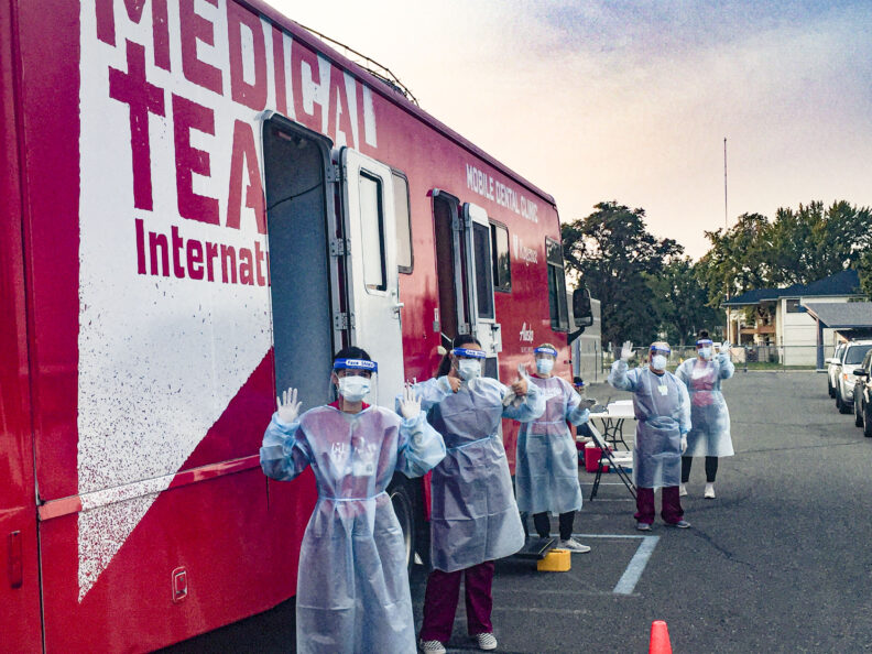 students in PPE standing outside mobile coach