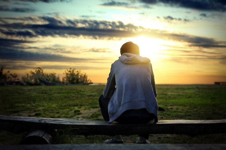 teenager looking at the sunset over a field